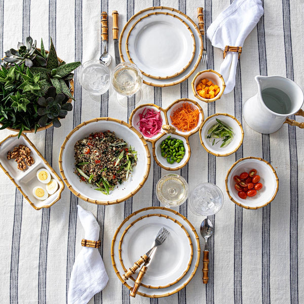 Classic Bamboo 11-inch ceramic serving bowl in natural, filled with salad on a striped tablecloth.
