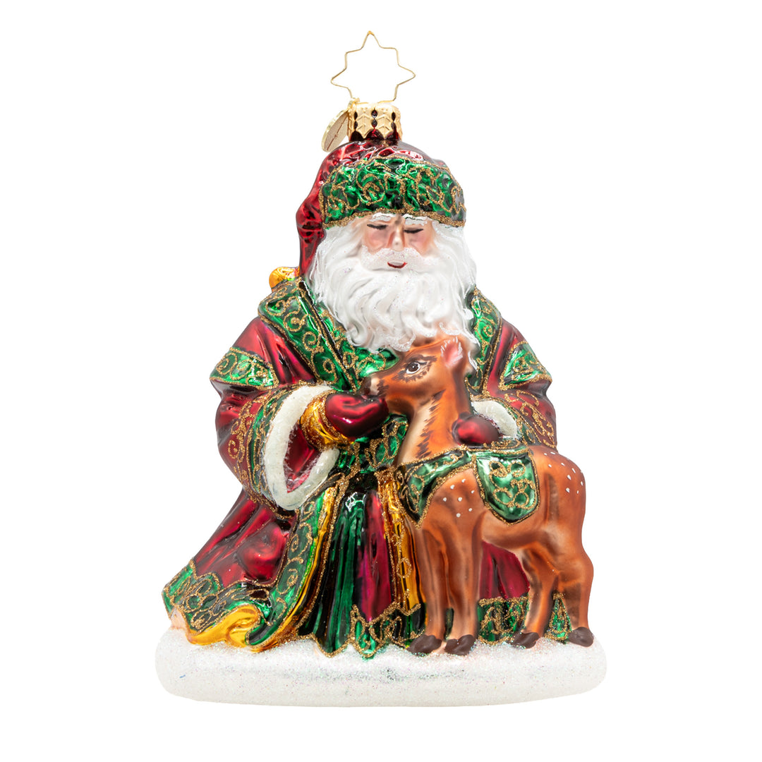 Glass Santa ornament in a red and green robe holding a small brown fawn on a snowy base.