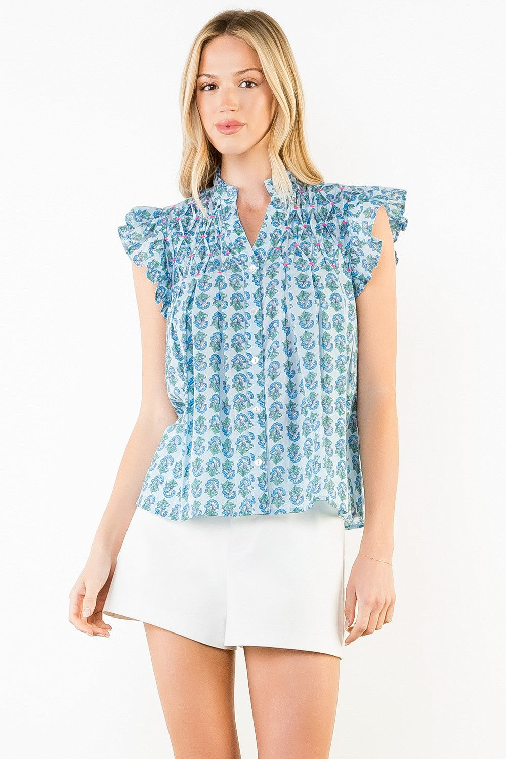 Woman wearing the Natalie Flutter Sleeve Floral Pattern Top in blue with white shorts.