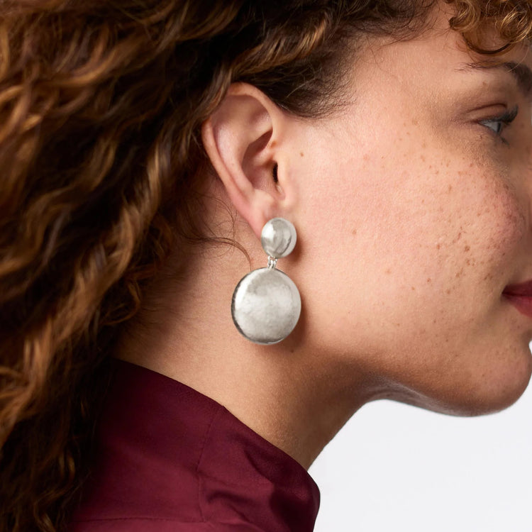 Woman wearing Solara Statement Earrings in silver, featuring two tiered hammered metal discs.