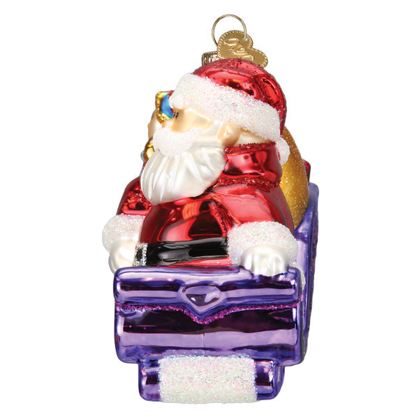 Santa Claus in a purple sleigh with a gold gift bag, a glass Christmas ornament with glitter trim.