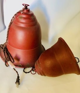 Small red metal bell-shaped ceiling light fixture with a soft glow.