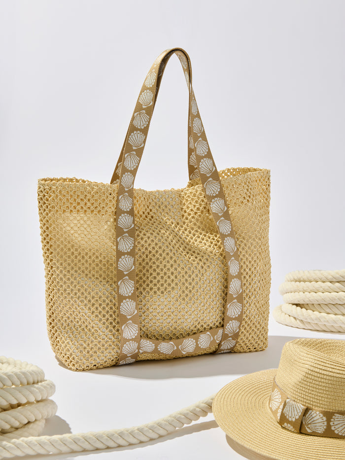 Tan paper straw tote with shell-print straps holding a matching adjustable hat