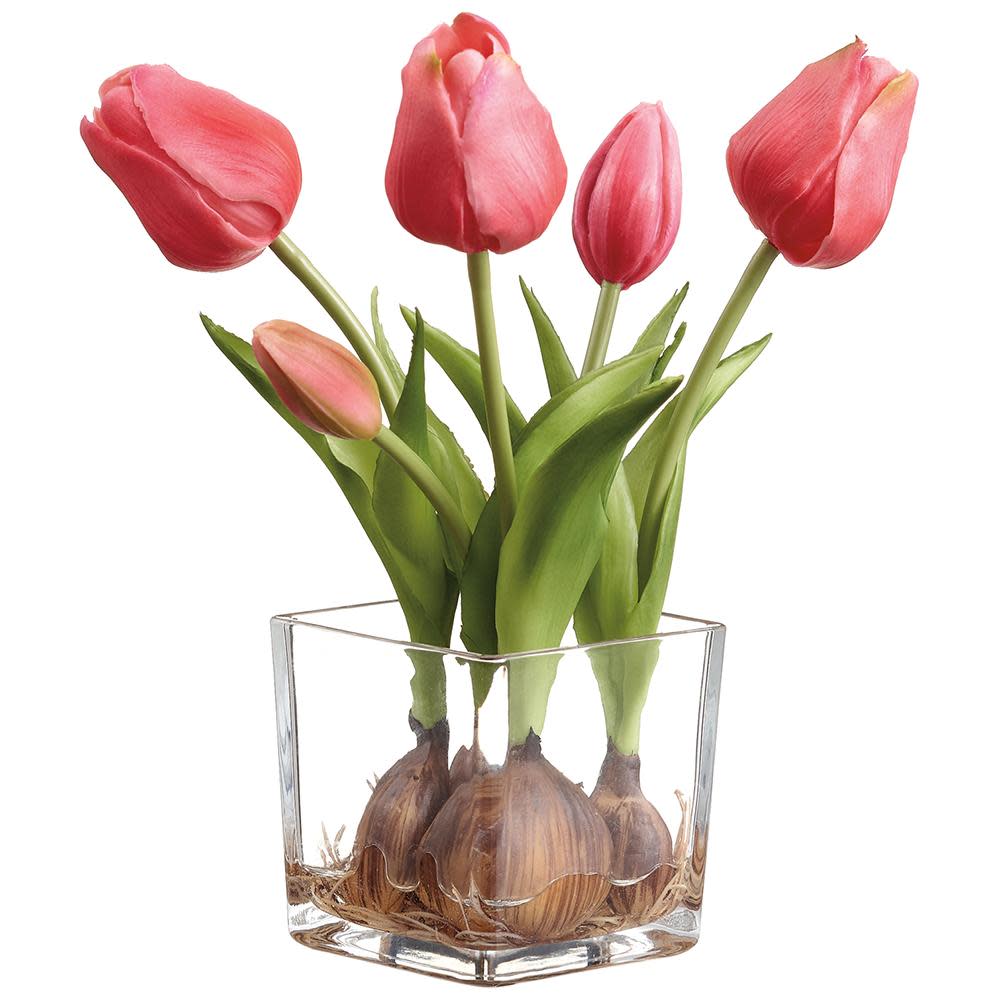 Pink artificial tulips with bulbs in a square clear glass vase.