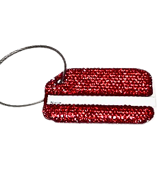 A rectangular luggage tag covered in sparkling red rhinestones with a steel wire attachment loop.