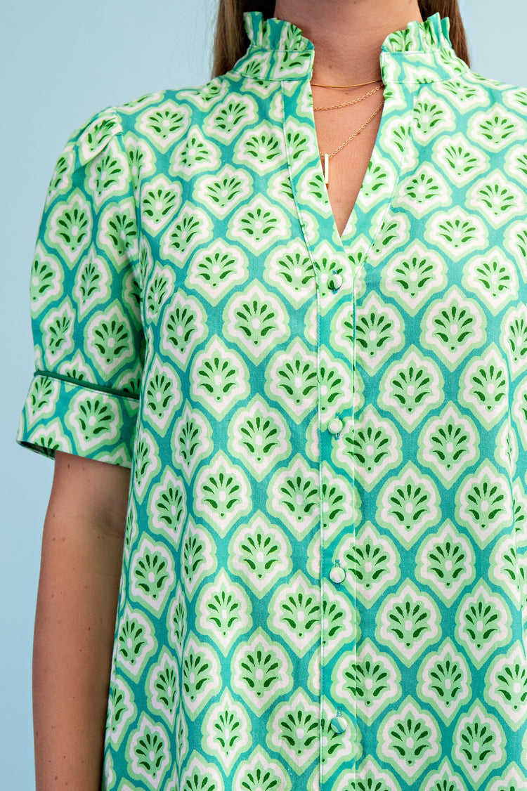 Close-up of a green and white printed midi dress with a ruffled collar and button-down front.