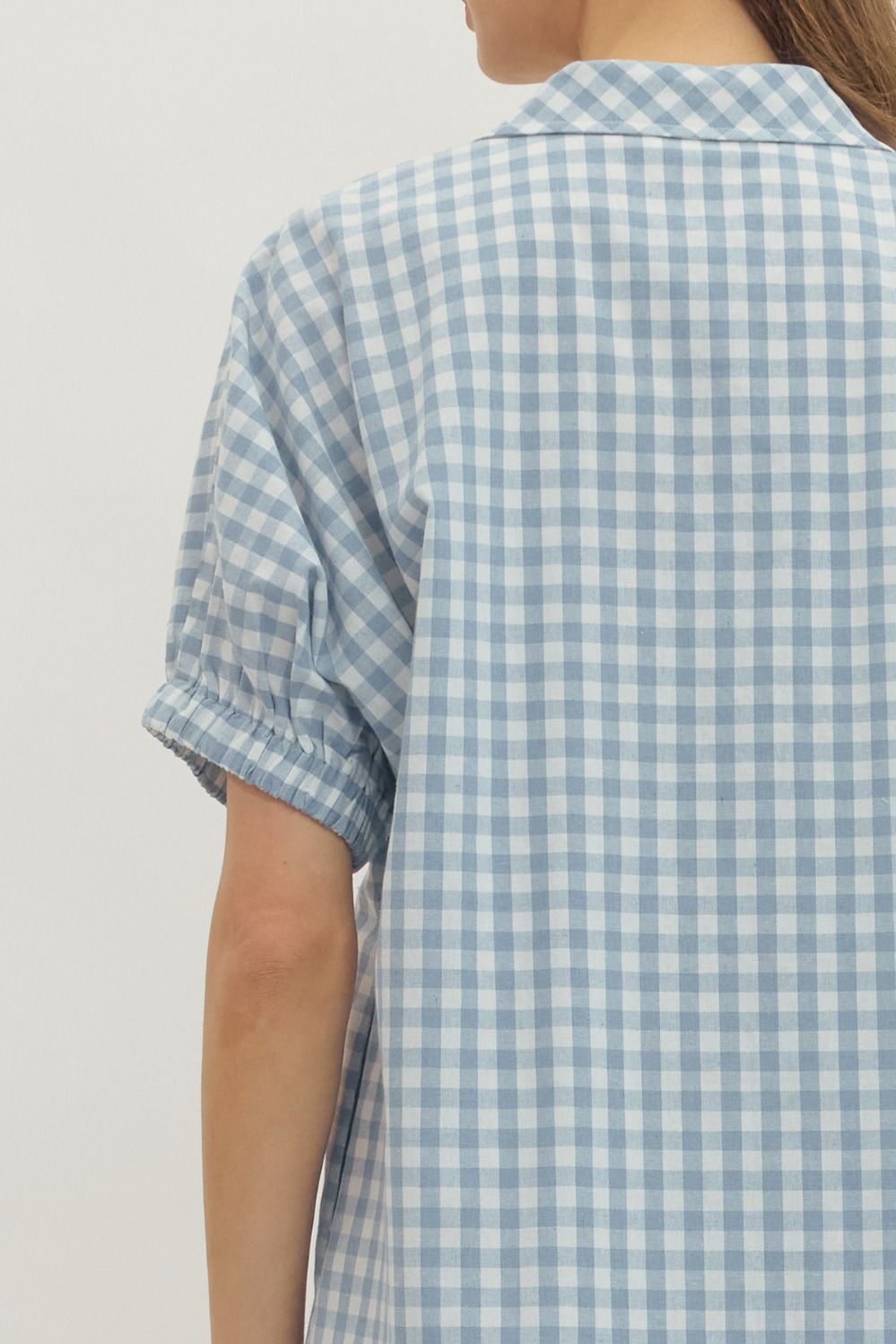 Back view of a light blue and white gingham short sleeve dress with elasticated cuffs.