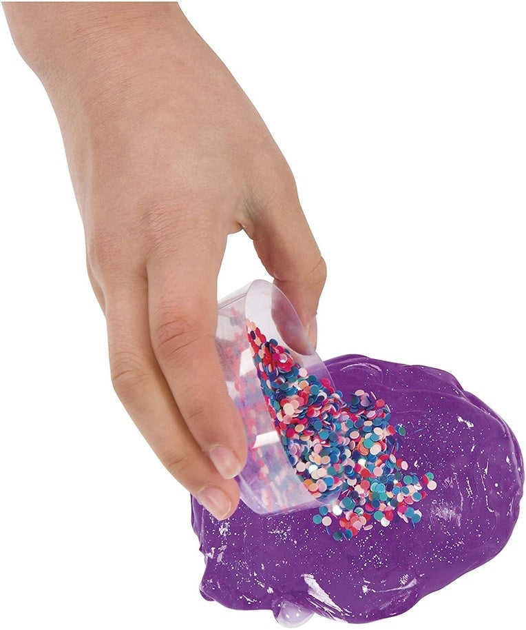 A cup of colorful slime topped with confetti mix-ins in a clear container.