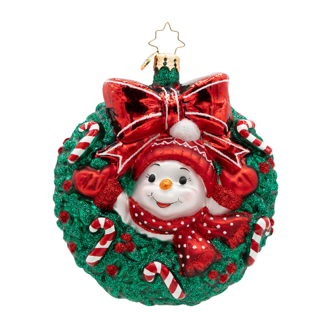 Snowman ornament inside a green wreath with candy canes and a large red bow.