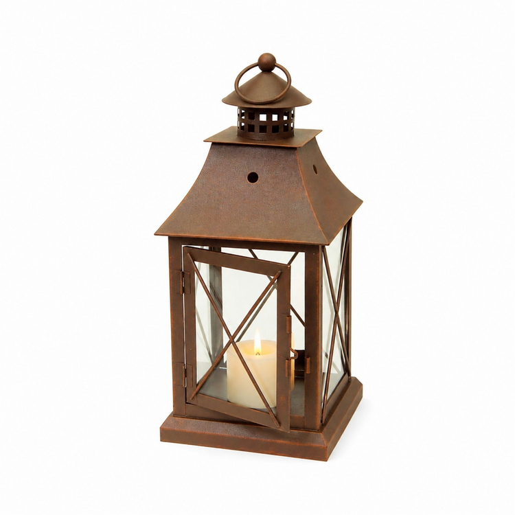 Rustic brown metal decorative lantern with a lit pillar candle inside and a ring handle on top.