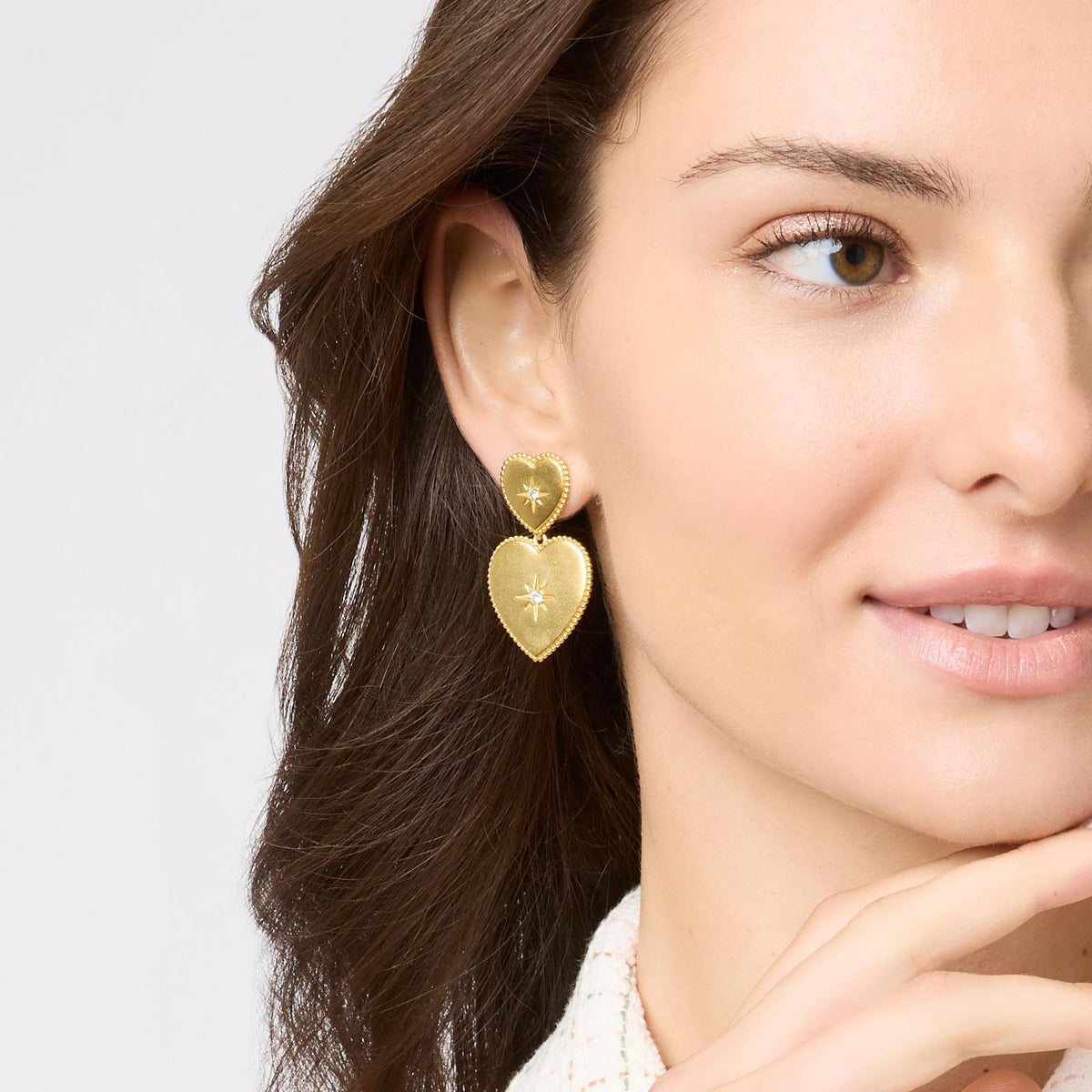 Model wearing Heart Statement Earrings in 24K gold plate with CZ starburst details.