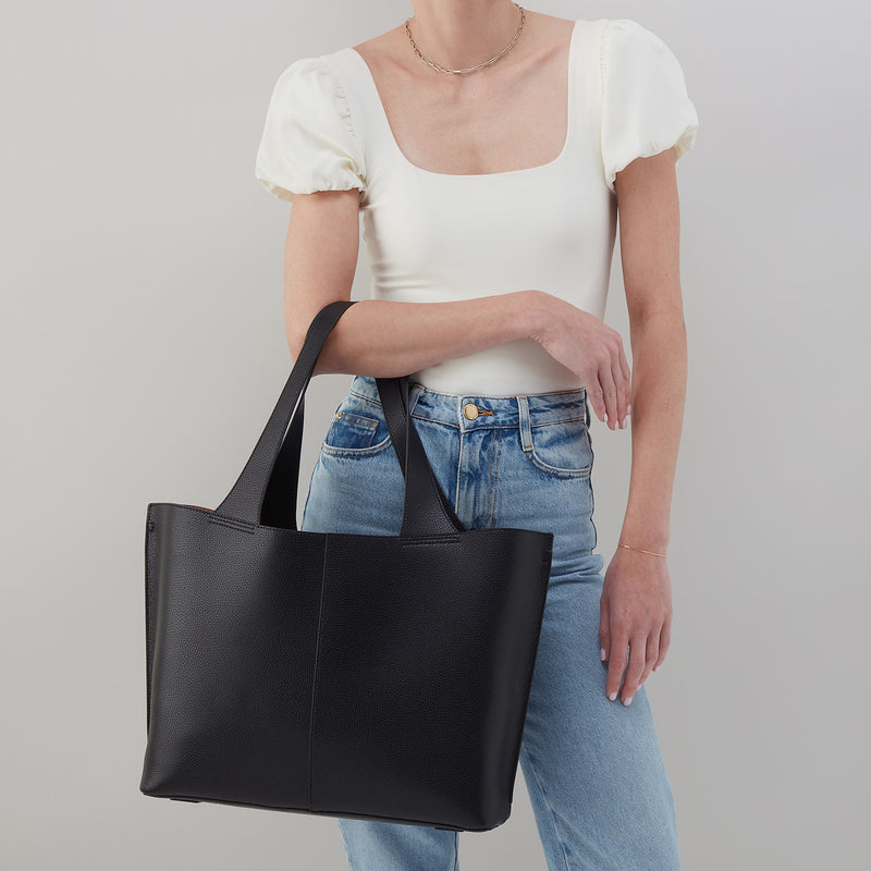 Vida large tote in solid leather with brushed antique brass hardware, coconut shell interior lining, and double straps.