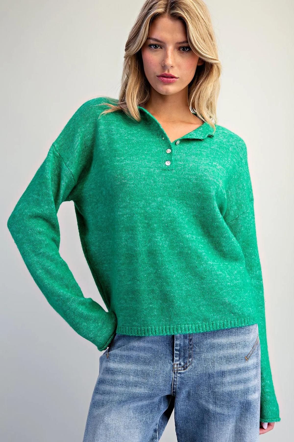 Woman wearing the Donna Long Sleeve Knit Sweater in green with a buttoned collar and blue jeans.