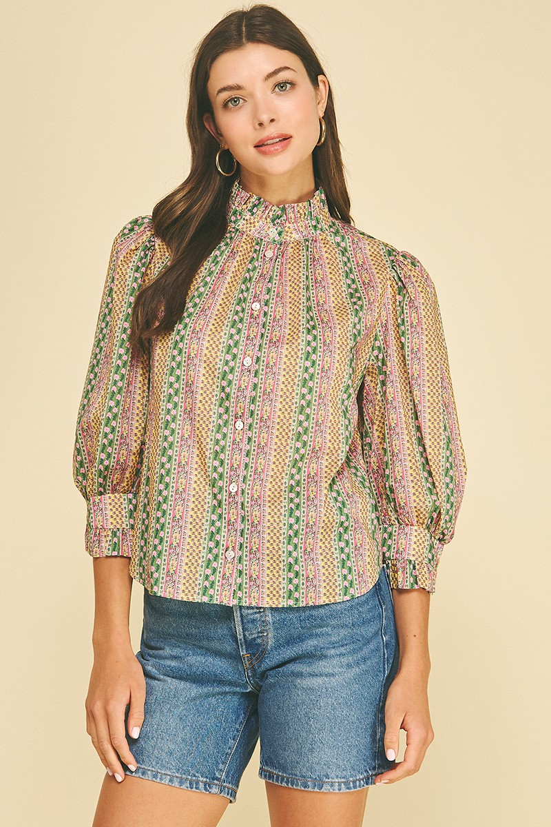 Woman wearing a Mabel floral botanical print button-down blouse with a ruffled high neck.