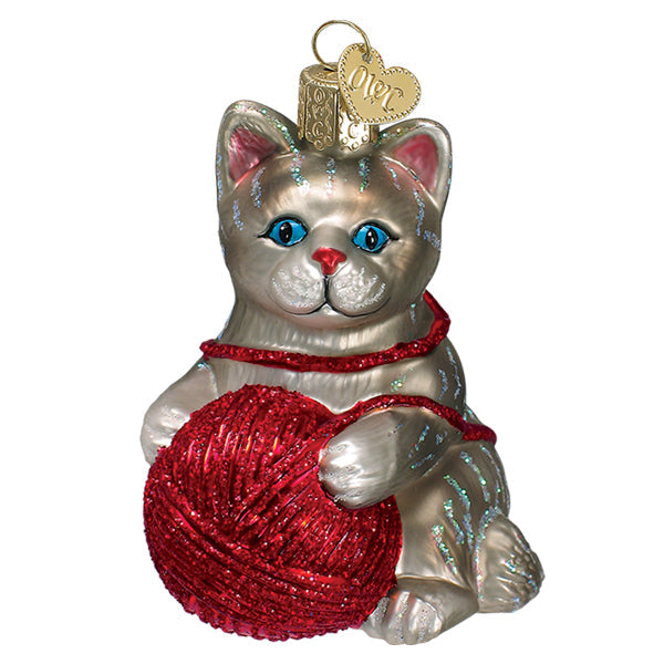 Grey glass kitten ornament with blue eyes playing with a red glittered ball of yarn.
