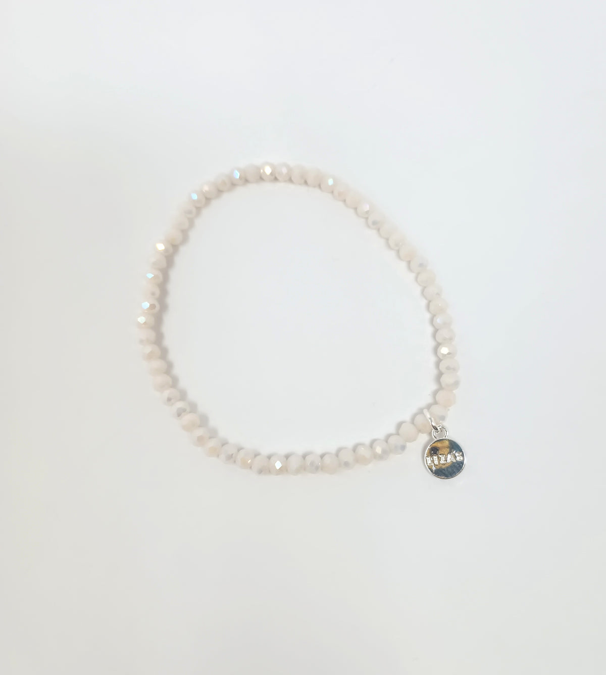 Stretchy bracelet with faceted white glass beads and a small silver circular charm.