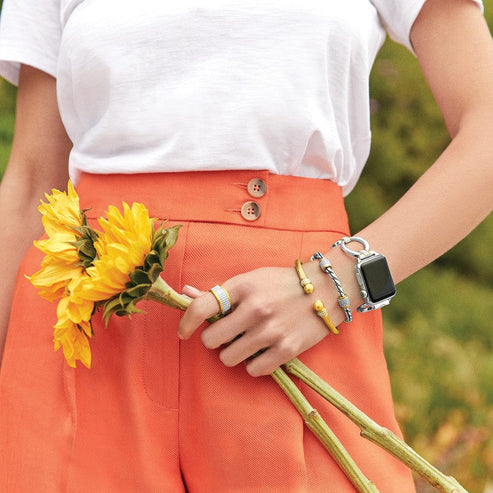 A person wearing a silver and gold Meridian Tempo Watch Band on an Apple Watch with bracelets.