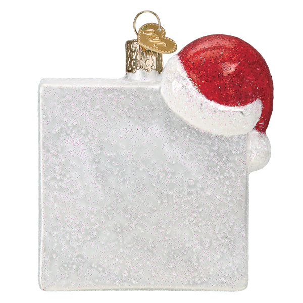 Square white glitter glass ornament with a red Santa hat on the top corner.