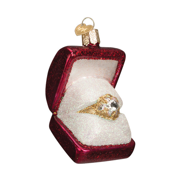 Red glittered glass ring box ornament open to reveal a gold ring with a large sparkling gem.