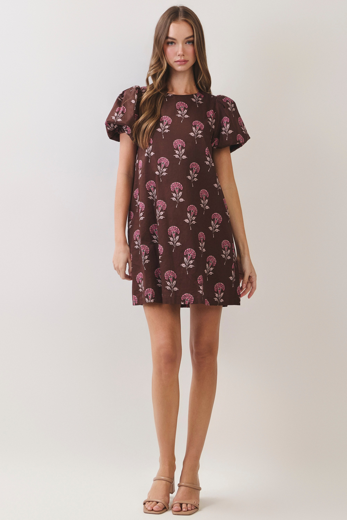 Woman wearing a brown Lily Floral Print mini dress with short puff sleeves and a round neckline.