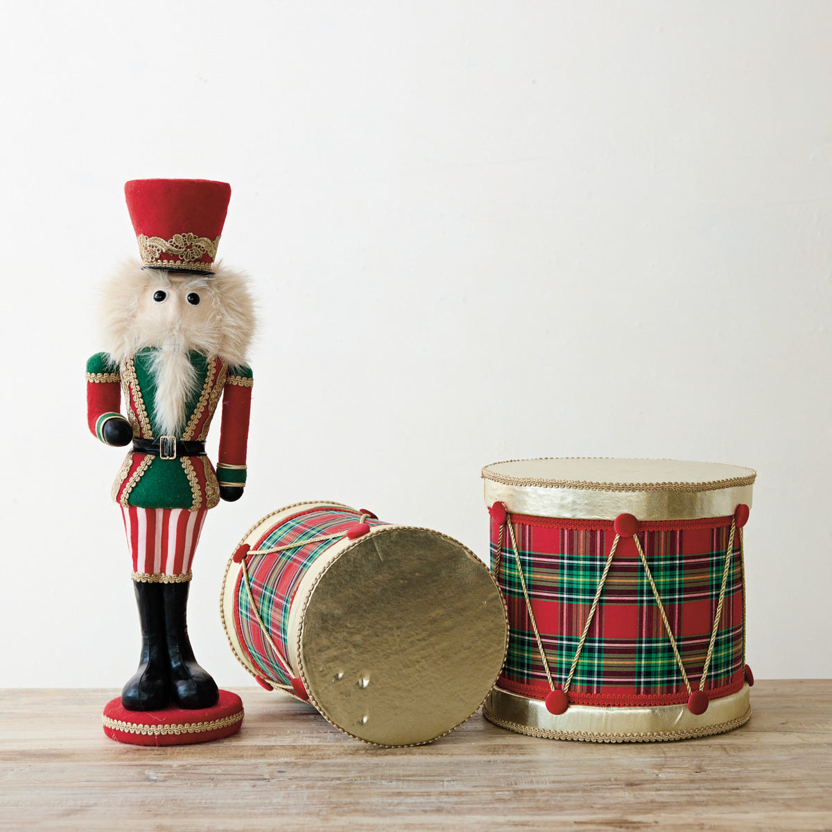 Foam and fabric decorative drum with a red and green plaid pattern and gold trim.