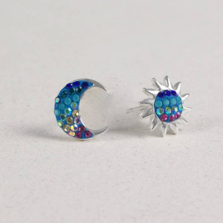 Sterling silver stud earrings featuring a crescent moon paired with a sun silhouette set in Austrian crystals.