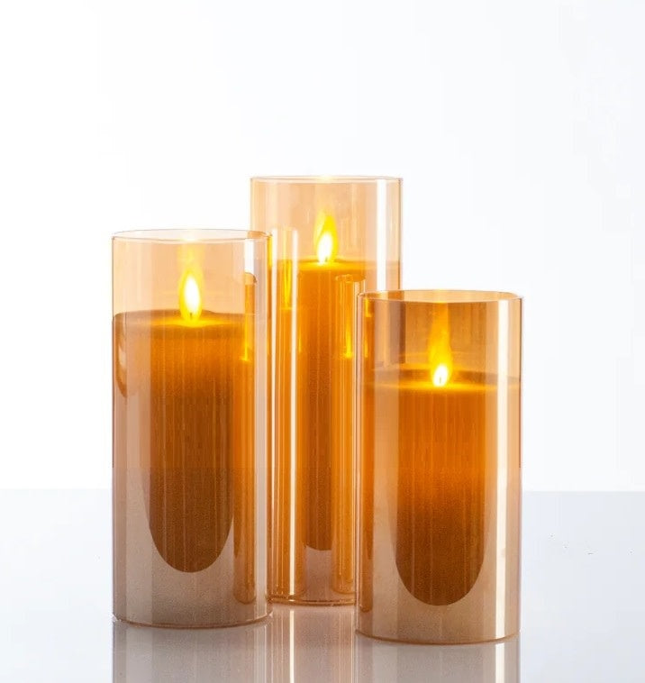 Amber paraffin wax pillar candle with realistic moving flame LED technology inside clear glass.