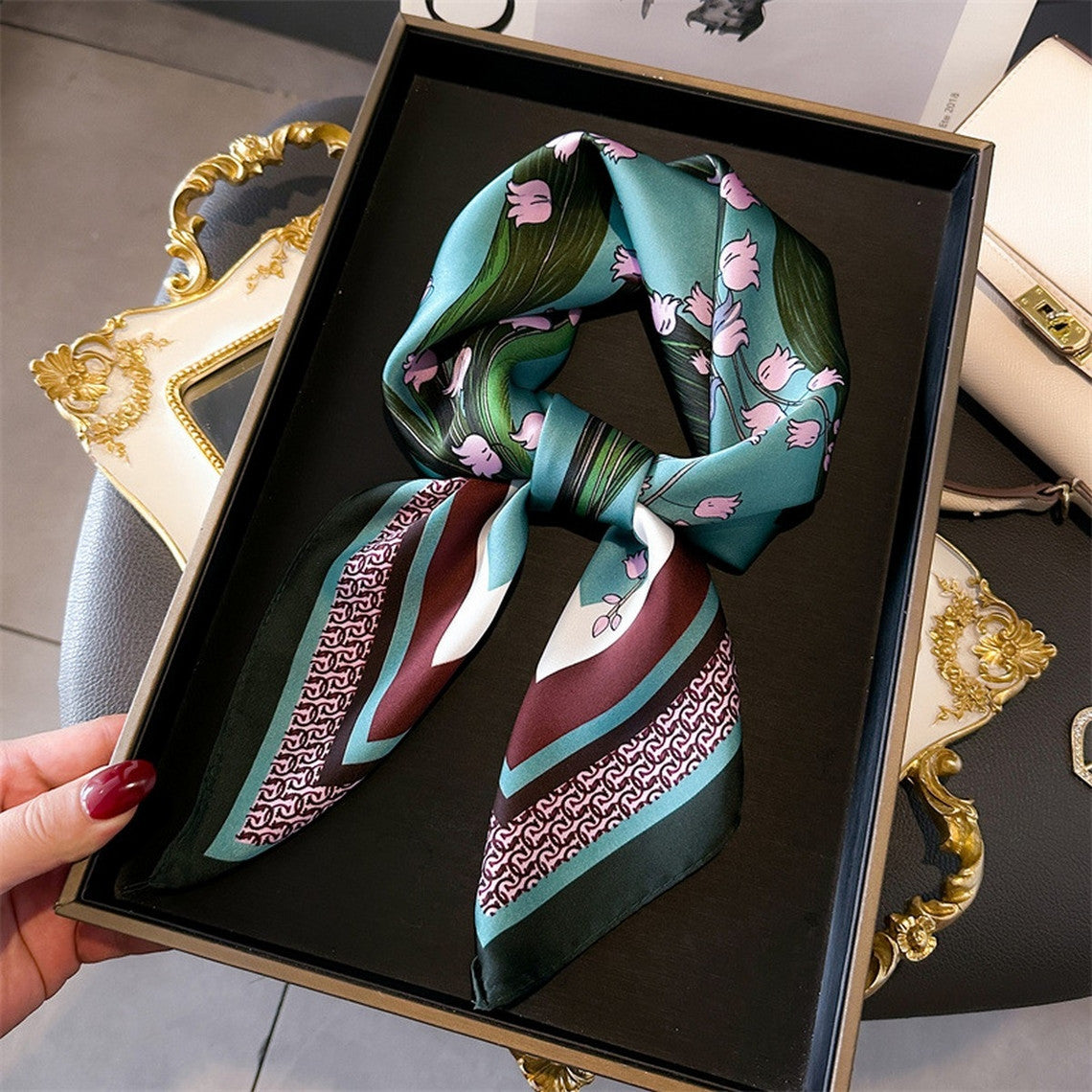 Artistic printed small square scarf in teal with pink floral patterns and geometric borders.