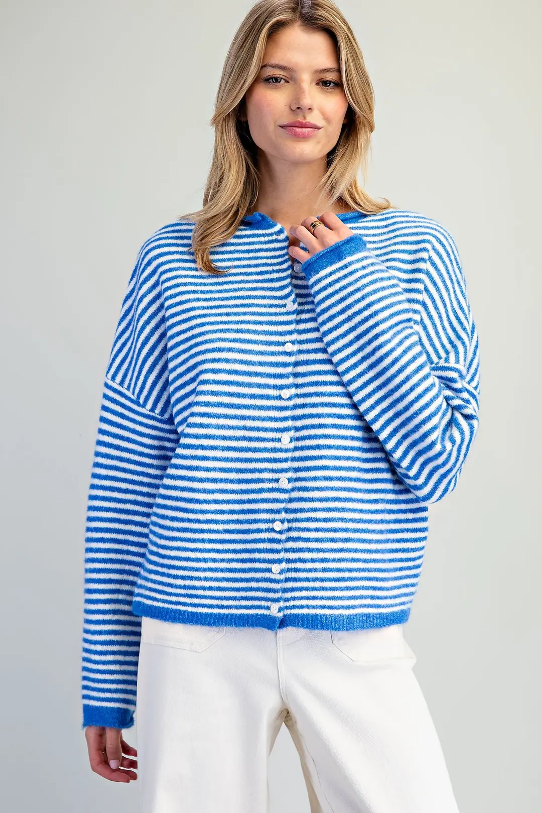 Woman wearing a blue and white horizontal striped knit cardigan with a button-front and crew neck.