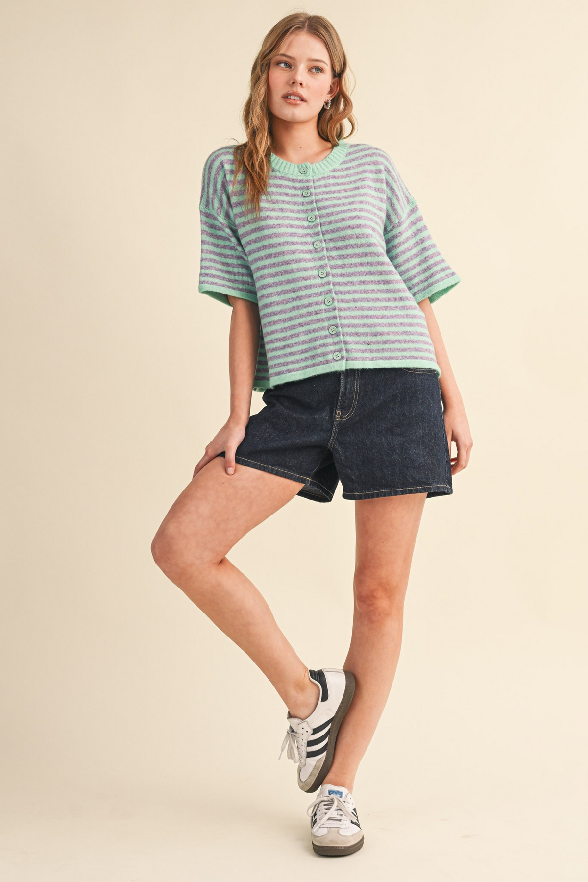 Model wearing the Ivy Striped Short Sleeve Sweater Cardigan in mint and purple with denim shorts.