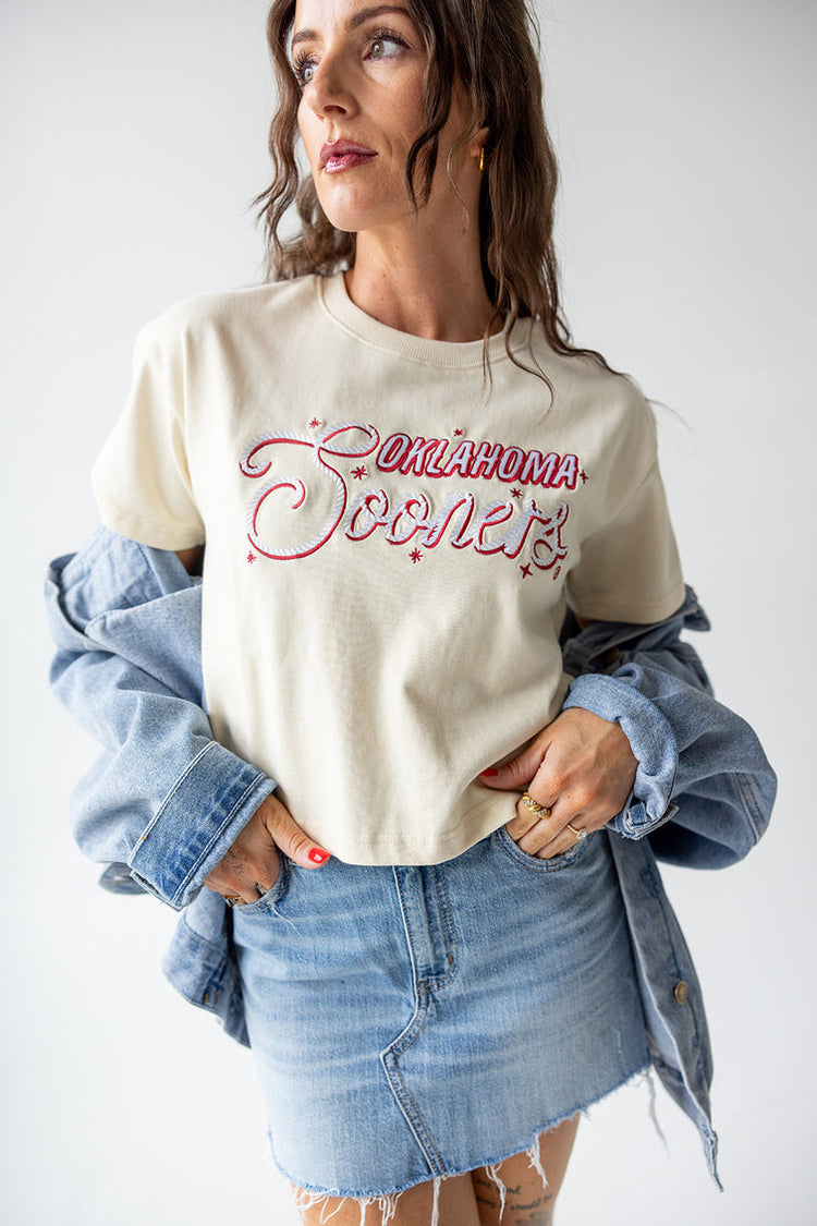 Woman wearing a Mandy Oklahoma Lasso Luxe Heavyweight Crop Tee with a denim jacket and skirt.