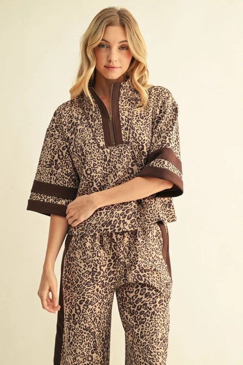 Woman wearing a leopard print faux suede top with a half-zip collar and brown contrast trim.