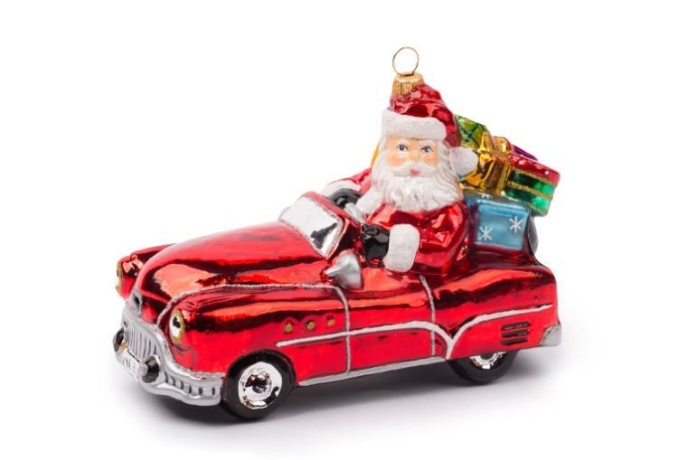 Hand-painted glass Santa in a red vintage Oldsmobile car ornament with gifts in the back.