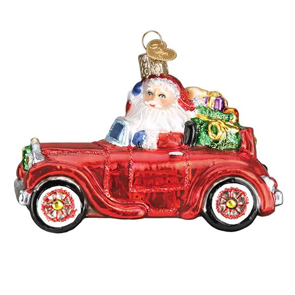 Glass Christmas ornament of Santa Claus driving a red antique car filled with colorful gifts.