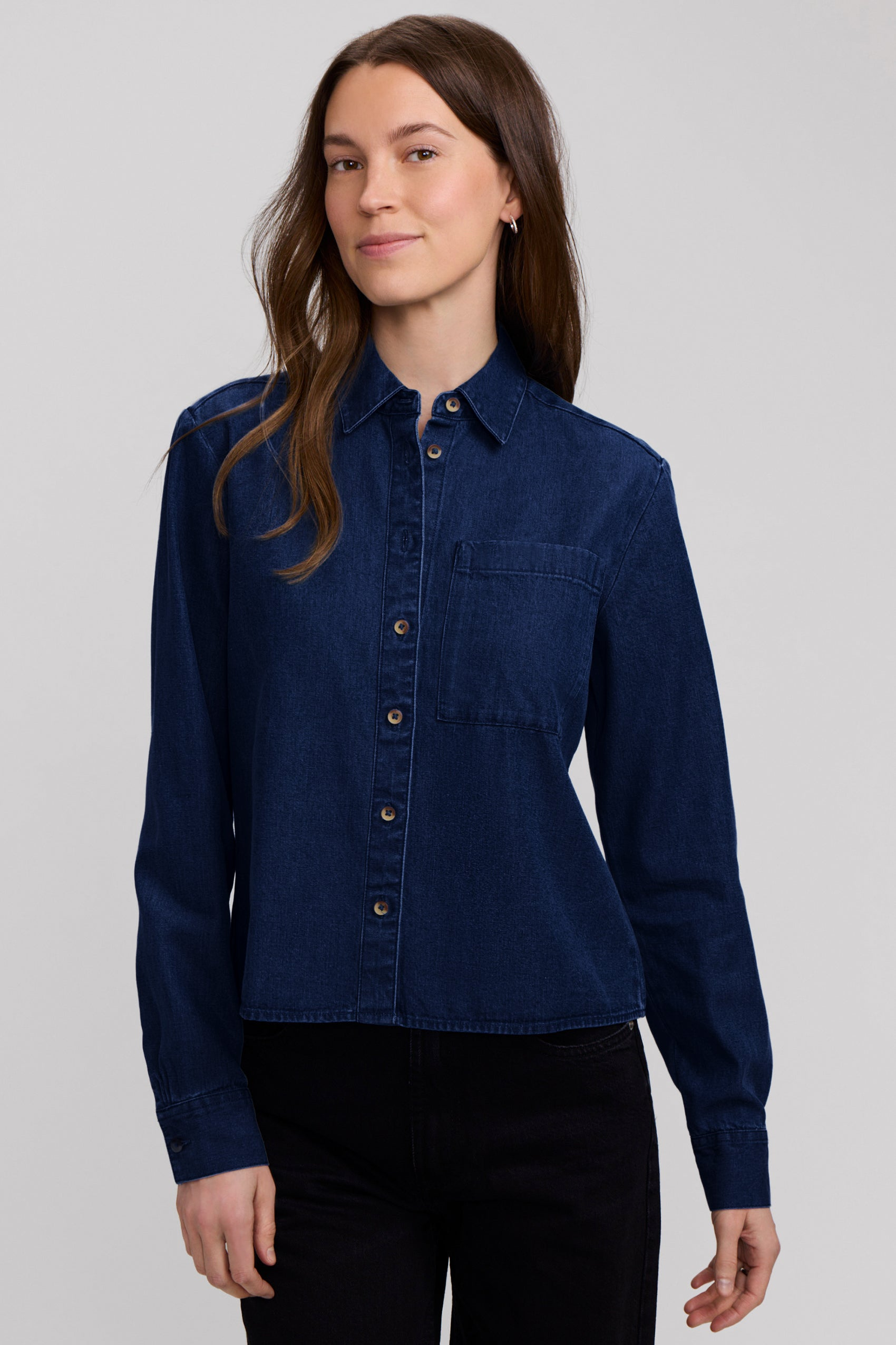 Woman wearing the Jodie Denim Long Sleeve Short Shirt in a dark indigo wash with black pants.