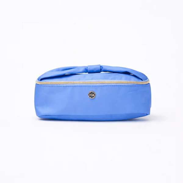 Cornflower blue makeup bag with an oversized bow handle and gold metal hardware.