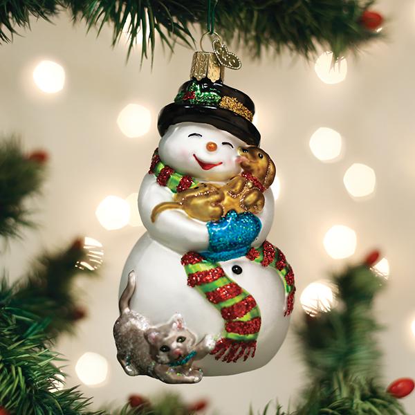 Glass snowman ornament wearing a black hat and striped scarf, holding a puppy and a kitten.