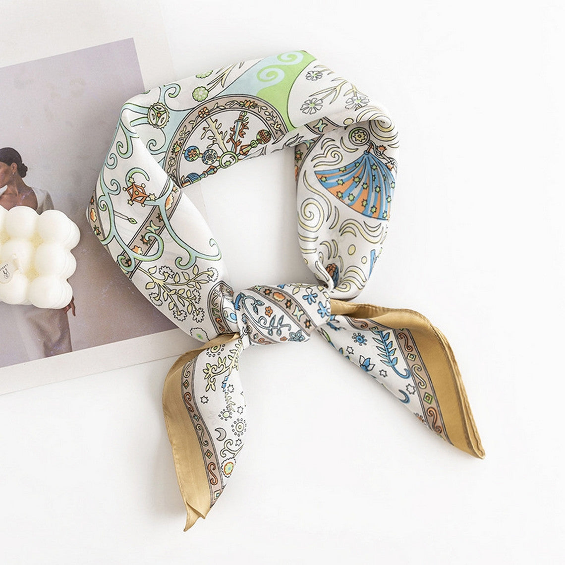 Floral satin square scarf with intricate patterns and gold borders, tied in a knot.