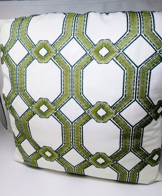 White 24x24 pillow with a green geometric embroidered pattern.