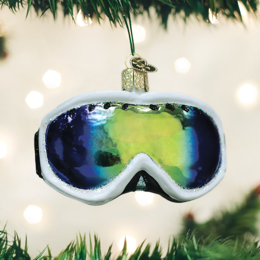 Glass ski goggles ornament with white frame and iridescent blue and yellow lens on a tree.