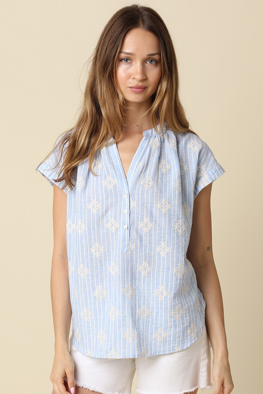 Woman wearing the Maxine Short Sleeve Print Blouse in light blue with white stripes and embroidery.