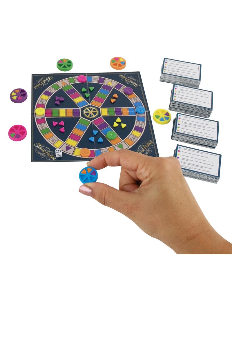 A person's hand holding a miniature blue game token from the World's Smallest Trivial Pursuit game.