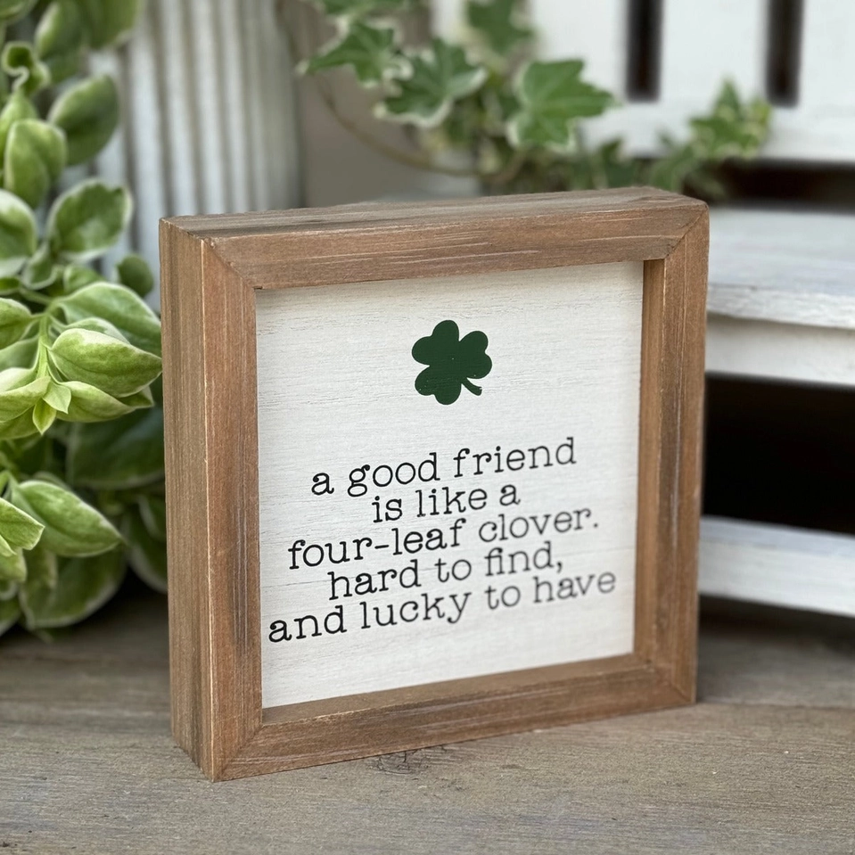 Six-inch square wooden frame with white background featuring black text about a four-leaf clover and green shamrock artwork.