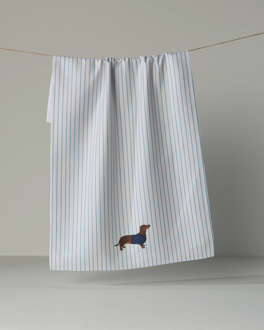 White and blue striped tea towel with an embroidered dachshund wearing a blue sweater.