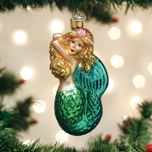 Seashell Mermaid glass ornament with golden hair and a glittery green tail on a Christmas tree.