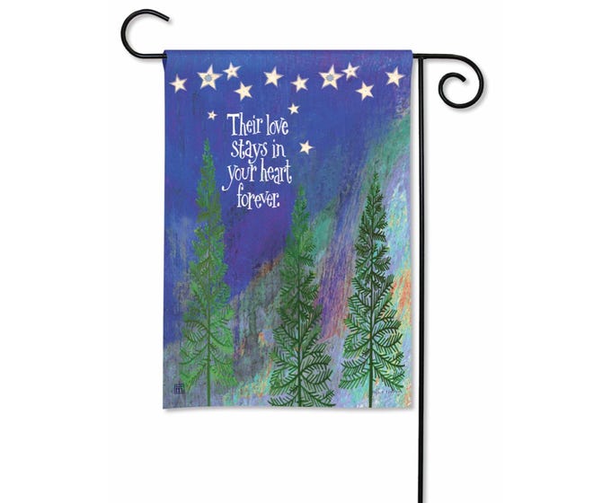 Garden flag with evergreen trees under a starry night sky with aurora borealis and the text 'Their love stays in your heart forever.'