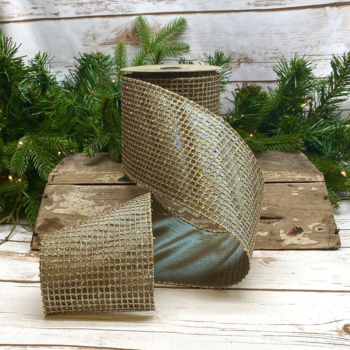 4 inch wide gold taffeta glitter mesh ribbon on a spool, displayed on a rustic wooden crate.