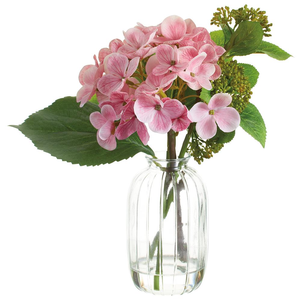 Pink hydrangea arrangement in a clear glass vase with green foliage