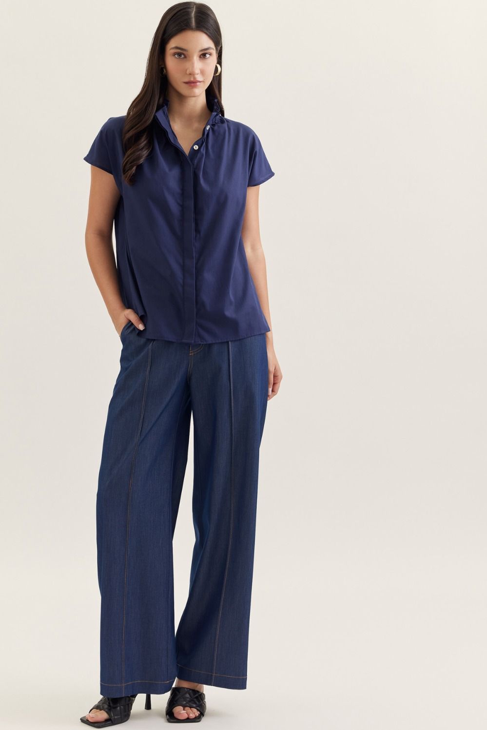 Woman wearing the Aliana Solid Cap Sleeve Top in navy blue with wide-leg denim jeans.