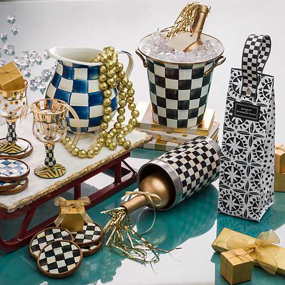 Courtly Check wine cooler on a table with a gold bottle, ice bucket, pitcher, and gift bag.